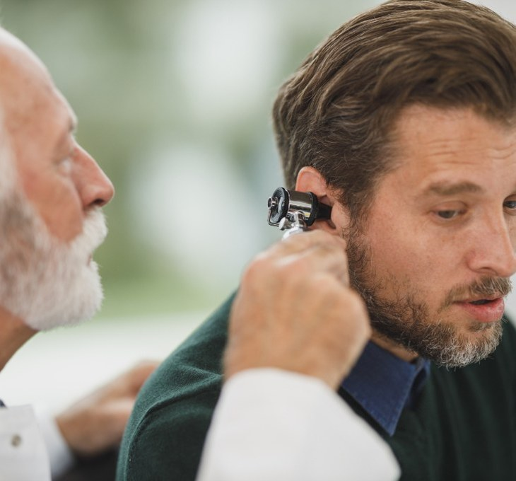 A clinician examining a patient's ear with an otoscope